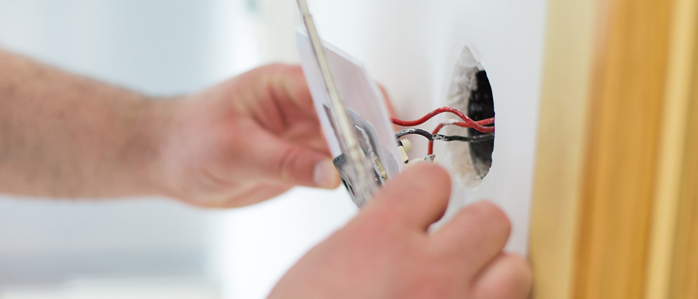 electrician fixing a plug socket to wall